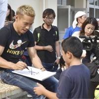 Japan national team and Galatasaray defender Yuto Nagatomo signs autographs on July 18 during an event at a school in Ozu, Ehime Prefecture,  a city near his hometown Saijo that was hit hard by deadly torrential rains. | KYODO