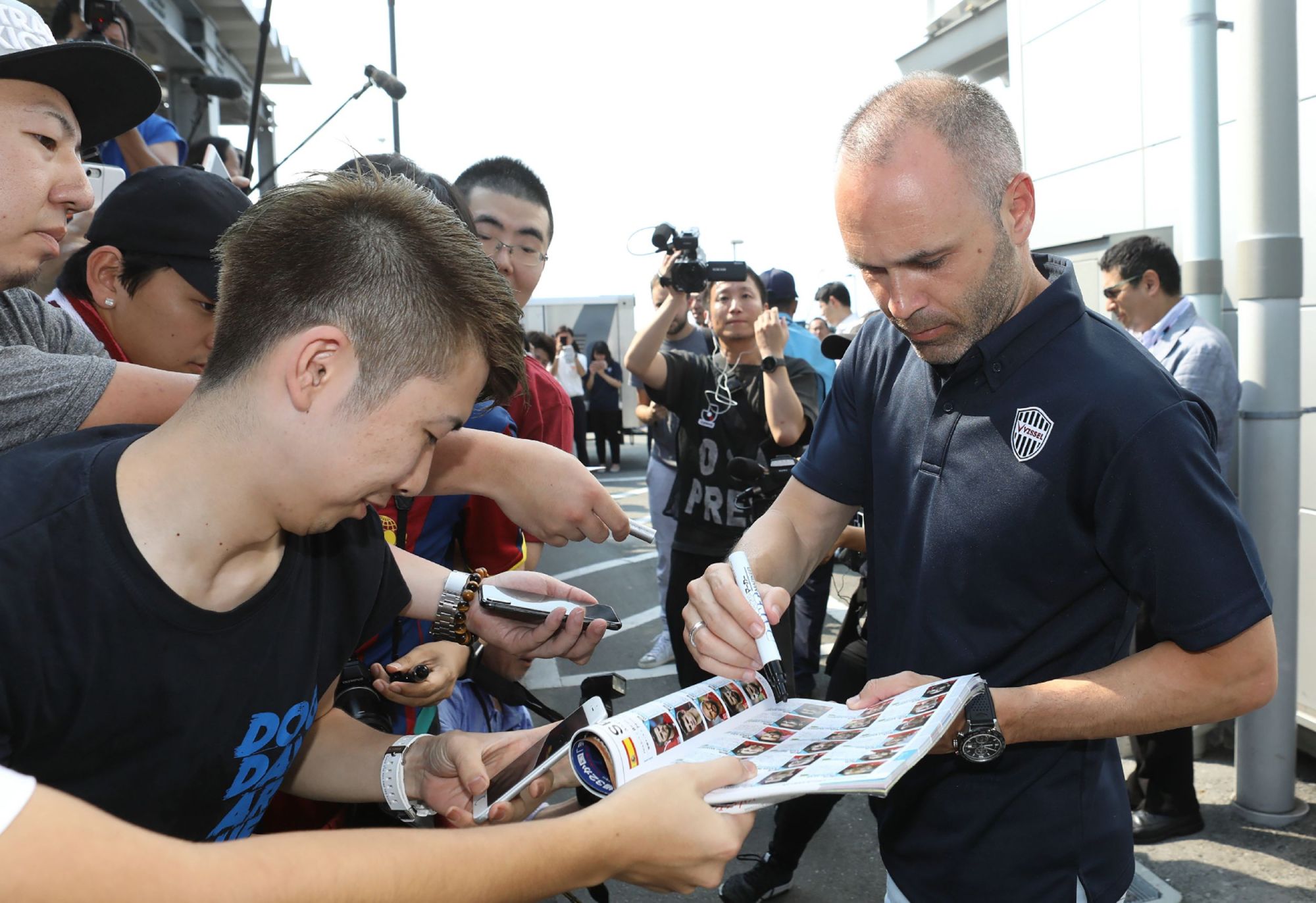 Andres Iniesta signs autographs after arriving at Kansai International Airport on Wednesday. | AFP-JIJI