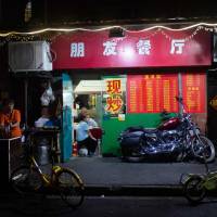 This picture taken Sunday shows a Harley-Davidson motorcycle parked in front of a restaurant in Shanghai. From Harley-Davidson motorcycles and American bourbon to Chinese parts and machinery, the world\'s two largest economies have exchanged punitive tariffs that slice through a wide swath of products. | JOHANNES EISELE / VIA AFP-JIJI