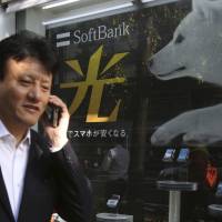 A man walks past a SoftBank advertisement in Tokyo. The firm said Monday its group net profit in the April-June period jumped as its investments through its Vision Fund are paying off. | AP