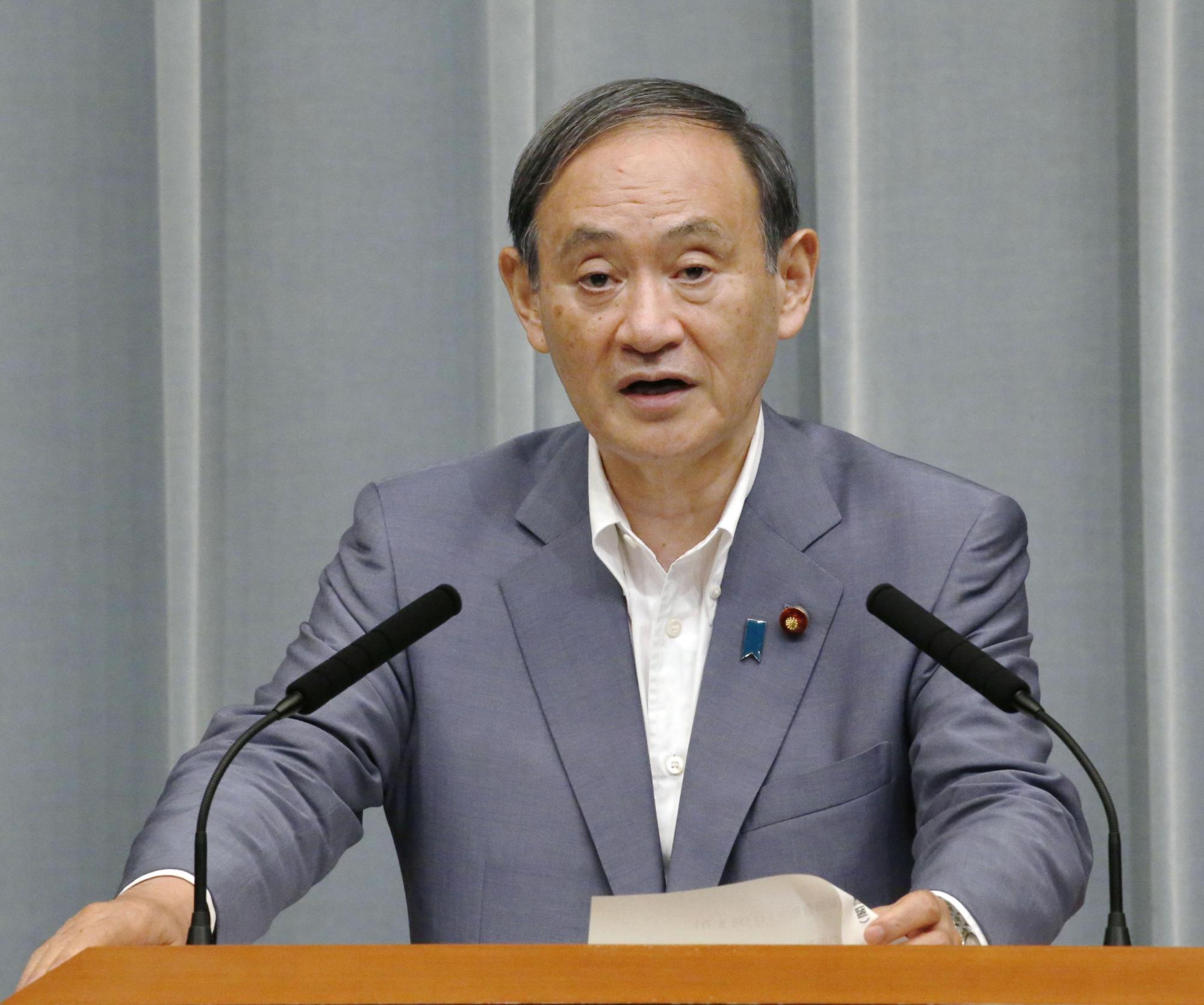 Chief Cabinet Secretary Yoshihide Suga speaks during a regular news conference at the Prime Minister's Office in this photo taken in August. On Tuesday Suga said mobile phone operators could cut phone bills by about 40 percent, pushing down the stock prices of those firms. | KYODO