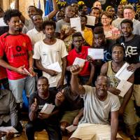Sudanese migrants arrived in France with the rescue ship Aquarius pose with their refugee identity certificates after a ceremony with the Mayor of Lille Martine Aubry and the Prefect of Hauts-de-France region Michel Lalande on Friday at the City Hall in Llille, northern France. | AFP-JIJI