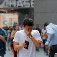 People react to a swarm of bees in Times Square in New York City Tuesday. | BRENDAN MCDERMID / VIA REUTERS