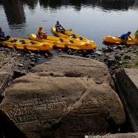 People in canoes visit one of the \'hunger stones\' revealed by the low level of water in the Elbe River in Decin, Czech Republic, Wednesday. | DAVID W CERNY / VIA REUTERS