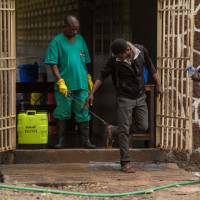 An attendant charged to handle access to the Ebola security zone disinfects shoes outside the Wangata Reference Hospital in Mbandaka, northwestern Democratic Repubic of Congo., in May. Congo on Aug. 1 reported an outbreak of Ebola in the east of the vast country, barely a week after it had declared the end to an outbreak in the northwest. | AFP-JIJI