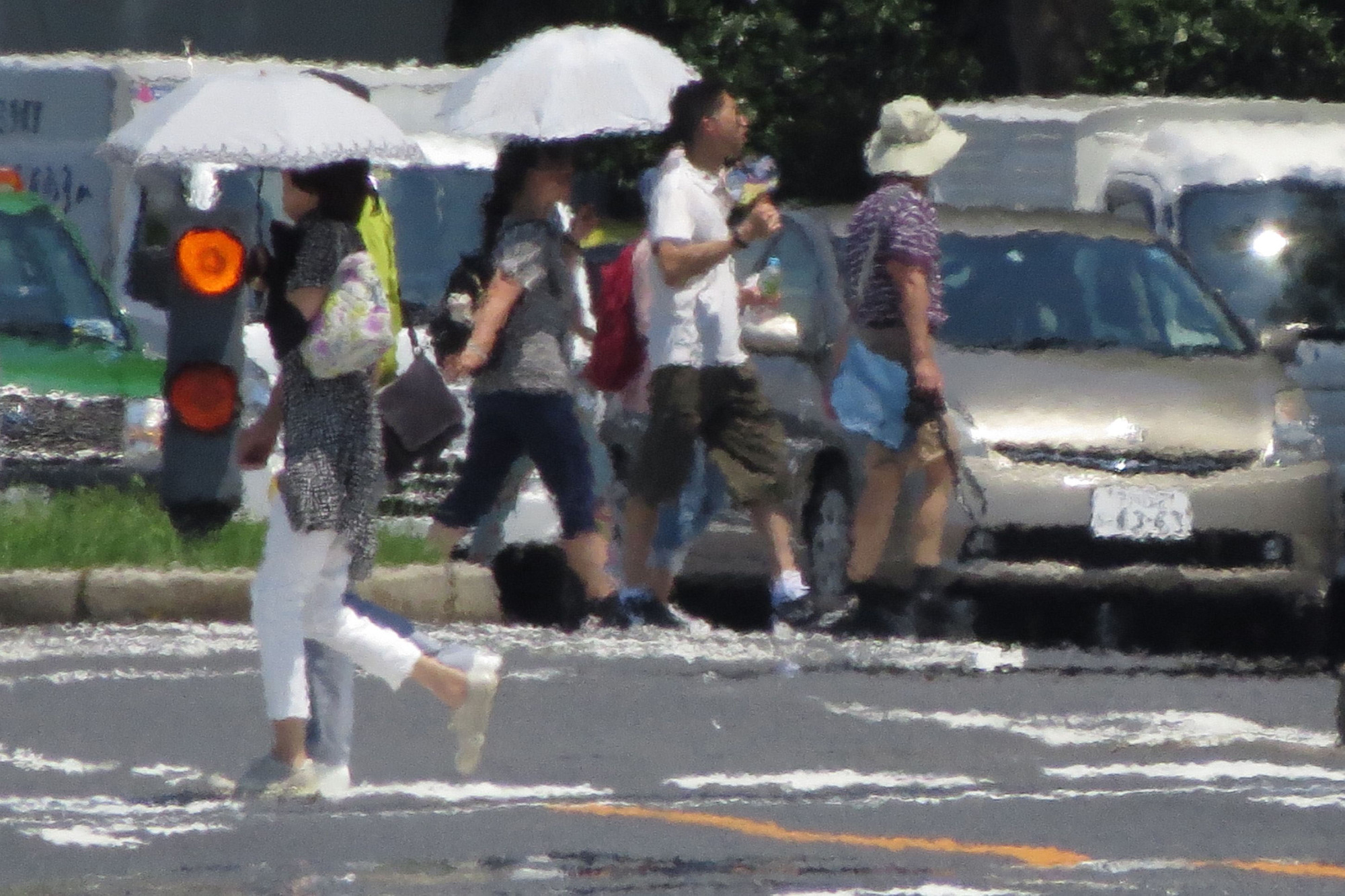 A heat haze is seen as pedestrians cross a street during a heat wave in Tokyo on Aug. 2. A new U.S. climate plan, expected to be released within days by President Donald Trump, comes during a summer dominated by hotter-than-normal weather. But the plan, which will replace one put in place by Trump's predecessor, President Barack Obama, may actually increase greenhouse gas emissions. | AFP-JIJI