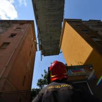 A firefighter looks up at the partially collapsed Morandi highway bridge in Genoa, Italy, on Thursday. | AP