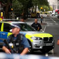 Armed police officers stand at a cordon after a car crashed outside the Houses of Parliament in Westminster, London, on Tuesday. | REUTERS