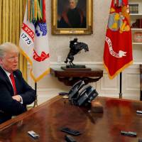 U.S. President Donald Trump answers a reporter\'s question as eight different phones and recording devices placed on his desk by reporters and White House staff record his words during an interview with Reuters in the Oval Office of the White House in Washington Monday. | LEAH MILLIS / VIA REUTERS