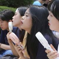 Middle school students use portable fans amid the sweltering heat during a rally demanding full compensation and apology from the Japanese government for wartime \"comfort women\" forced to provide sex at Japanese military brothels before and during World War II, in front of the Japanese Embassy in Seoul on Wednesday. | AP