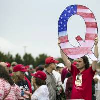 David Reinert holds a Q sign he waits in line with others to enter a campaign rally with President Donald Trump and U.S. Senate candidate Rep. Lou Barletta, R-Pa., Thursday in Wilkes-Barre, Pennsylvania. | AP