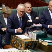 Australian Prime Minister Malcolm Turnbull answers a question from the opposition in Parliament as Treasurer Scott Morrison (second, right) and Minister for Home Affairs Peter Dutton (right) look on in Canberra on Monday. Australia shelved plans to embed carbon emissions targets in law on Monday after a party revolt against embattled Turnbull. | SEAN DAVEY / VIA AFP-JIJI