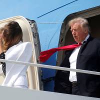 U.S. President Donald Trump and first lady Melania Trump are buffeted by the wind as they emerge from Air Force One arriving in Columbus, Ohio, on Friday. | REUTERS