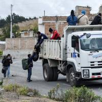Venezuelan migrants get on a truck on their way to Peru at the Panamerican highway in Tulcan, Ecuador, after crossing from Colombia on Tuesday. Ecuador announced on Aug. 16 that Venezuelans entering the country would need to show passports from Saturday onward, a document many are not carrying. And Peru followed suit on Friday, announcing an identical measure due to begin his Saturday. | LUIS ROBAYO / VIA AFP-JIJI