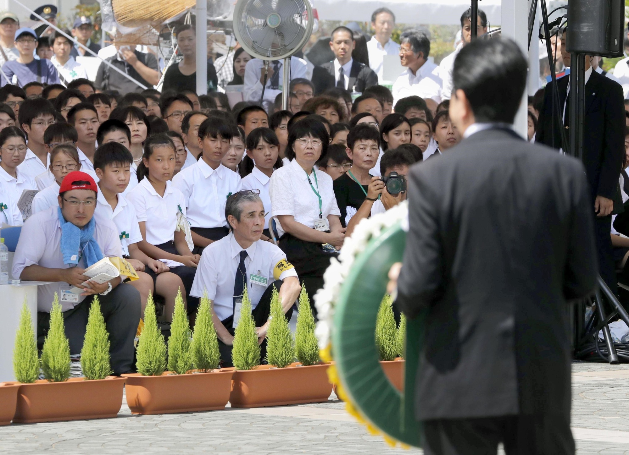 Attendees watch as Prime Minister Shinzo Abe presents a floral wreath Thursday at the annual ceremony to mark the 1945 atomic bombing of the city of Nagasaki. | KYODO