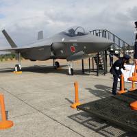 Air Self-Defense Force members set up cordons to protect a mock-up of an F-35 fighter jet during the annual Self-Defense Forces Commencement of Air Review at Hyakuri Air Base, north of Tokyo, in October 2014. | AP