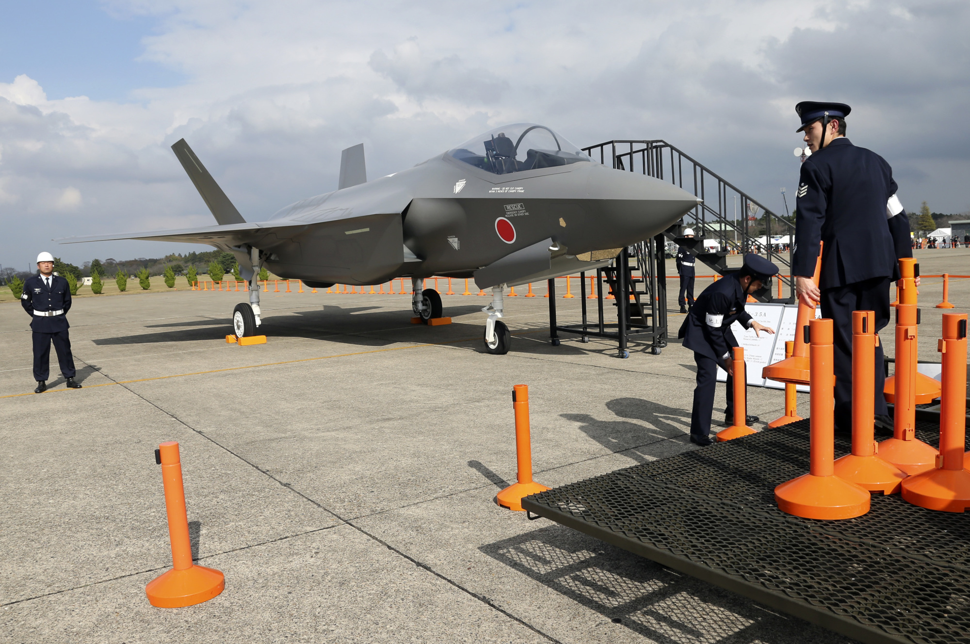 Air Self-Defense Force members set up cordons to protect a mock-up of an F-35 fighter jet during the annual Self-Defense Forces Commencement of Air Review at Hyakuri Air Base, north of Tokyo, in October 2014. | AP