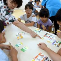 Children learn about sex through a card game at Terakoya Annex in Tokyo on Aug. 21. The recently opened cram school in Taito Ward offers unique programs, including one covering sex education. | SATOKO KAWASAKI