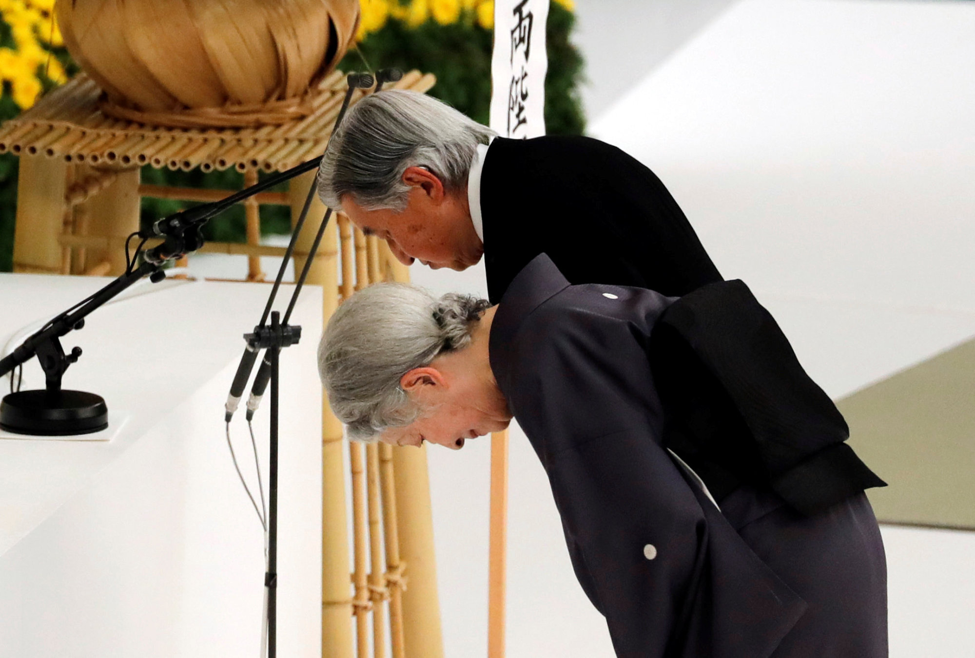 Emperor Akihito and Empress Michiko bow at an altar during a moment of silence for the war dead at a memorial ceremony marking the 73rd anniversary Wednesday of Japan's surrender in World War II. The event was held at the Nippon Budokan Hall in Tokyo. | REUTERS