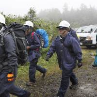 Police officers head to a mountainous area in Nakanojo, Gunma Prefecture, on Saturday to search an area where a helicopter crashed Friday. All nine people whho were aboard the aircraft were confirmed dead. | KYODO
