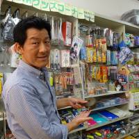 Hiroo Urakami shows a teapot designed for lefties at his stationery store in Sagamihara, Kanagawa Prefecture. | SARAH SUK