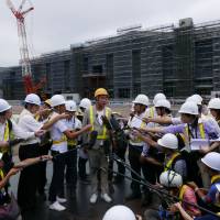 Architect Kengo Kuma speaks to reporters Wednesday in front of a new station being built on Tokyo\'s Yamanote line between its existing Shinagawa and Tamachi stations. | KAZUHIRO KOBAYASHI