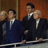 Tsuneo Watanabe (right) watches the opener for the Yomiuri Giants baseball team at Tokyo Dome along with Prime Minister Shinzo Abe on March 30. | KYODO