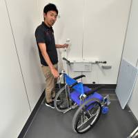 Yusuke Yamaguchi of the Paralympic Support Center demonstrates the Para Arena\'s barrier-free shower room, which is designed to allow access by athletes in wheelchairs. | YOSHIAKI MIURA