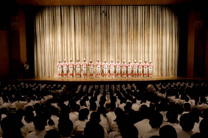 The team stands on stage during a pep rally before leaving for Koshien.