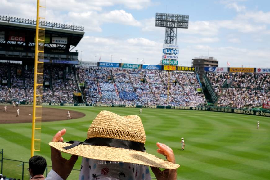 A fan adjusts a hat in the stands at Koshien Stadium.