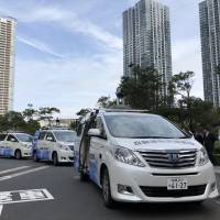 Self-driving cars are parked in front of the headquarters of NTT Data Corp. in Tokyo\'s Toyosu district on Thursday. | KAZUAKI NAGATA