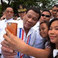 Philippines President Rodrigo Duterte poses for a selfie with students after a wreath-laying ceremony to commemorate National Heroes\' Day at the Heroes Cemetery in Manila on Monday. | AFP-JIJI