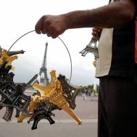 A souvenir vendor sells Eiffel tower models for tourists in front the Eiffel Tower at the Trocadero in Paris in 2011. | REUTERS