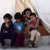 Children sit in the shade of a tent at a camp for the displaced in the rebel-held Syrian province of Idlib, at the village of al-Ghadfa, southeast of the province on Sunday. The Syrian regime and its Russian ally are threatening an offensive to retake the northwestern province of Idlib, Syria\'s last rebel bastion. | NAZEER AL-KHATIB / VIA AFP-JIJI