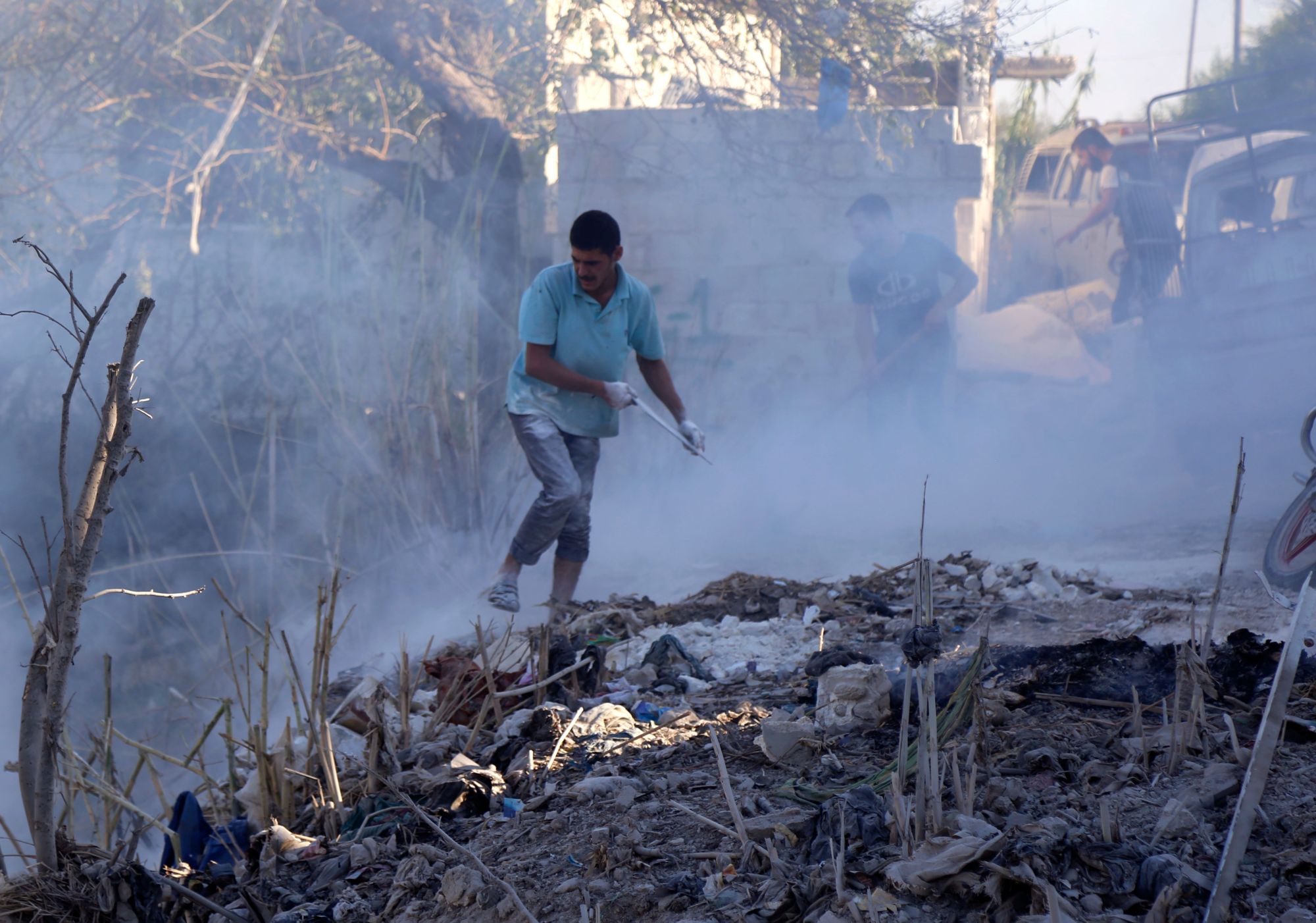 Syrians use dirt to put out a fire at the scene of a reported airstrike in the district of Jisr al-Shughur, in the Idlib province, on Tuesday. Russian warplanes battered Syria's rebel-controlled northwestern Idlib province on Tuesday for the first time in three weeks, the Syrian Observatory for Human Rights reported, as fears of a government offensive mount. | AFP-JIJI