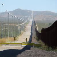 Stadium lights stand along a pedestrian barrier beside the border wall between Douglas, Arizona, and Agua Prieta, in the Mexican state of Sonora, in November 2016. | AP