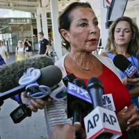 Raghida Dergham (center), a senior diplomatic reporter at the United Nations, updates reporters about her flight aboard an Emirates airliner after an emergency was declared when the plane landed at JFK Airport with ill passengers on a flight from Dubai Wednesday in New York. | AP