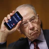 Senate Judiciary Committee Chairman Chuck Grassley holds up a timer on a smartphone to show Sen. Cory Booker how long he has been speaking for during a Senate Judiciary Committee hearing on Supreme Court nominee Judge Brett Kavanaugh on Friday in Washington. | AP
