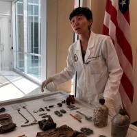 Jennie Jin, a forensic anthropologist who leads the Korea War Project at the Defense POW/MIA Accounting Agency (DPAA), shows some of the objects that accompanied the human remains handed over by North Korea, including a wallet, buttons and canteens, at Joint Base Pearl Harbor-Hickam, Hawaii, on Monday. | REUTERS