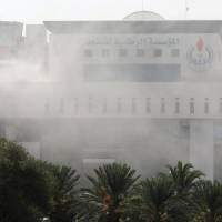 Smoke rises form the headquarters of Libyan state oil firm National Oil Corp. after gunman attacked it in Tripoli on Monday. | REUTERS