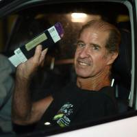Australian filmmaker James Ricketson waves from his car as he leaves for home from Sydney International airport on Sundeay. | AFP-JIJI