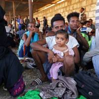 Migrants are seen after they were relocated from government-run detention centers, after getting trapped by clashes between rival groups in Tripoli Tuesday. | REUTERS