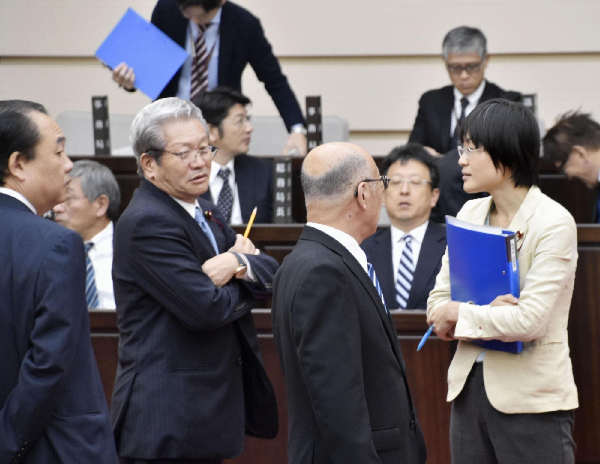 Kumamoto Municipal Assembly member Yuka Ogata is surrounded by fellow assembly members Friday after being criticized for asking questions from the podium while sucking on a cough drop. | KYODO