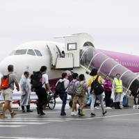 Passengers board a Peach Aviation flight bound for Hong Kong at Kansai International Airport on Saturday as the airport operator partially resumed international flights four days after being hit by a typhoon. | KYODO