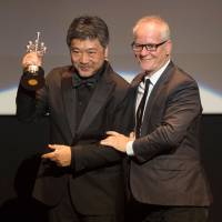Japanese director Hirokazu Kore-eda holds up the Donostia Award in recognition of his prestigious film career while standing beside Thierry Fremaux, general delegate of the Cannes Film Festival, during the 66th San Sebastian Film Festival in San Sebastian, northern Spain, on Sunday. | AFP-JIJI