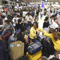 Passengers wait to check in at Narita airport\'s Terminal 2 on Tuesday after its automated system was hit by a glitch. | KYODO