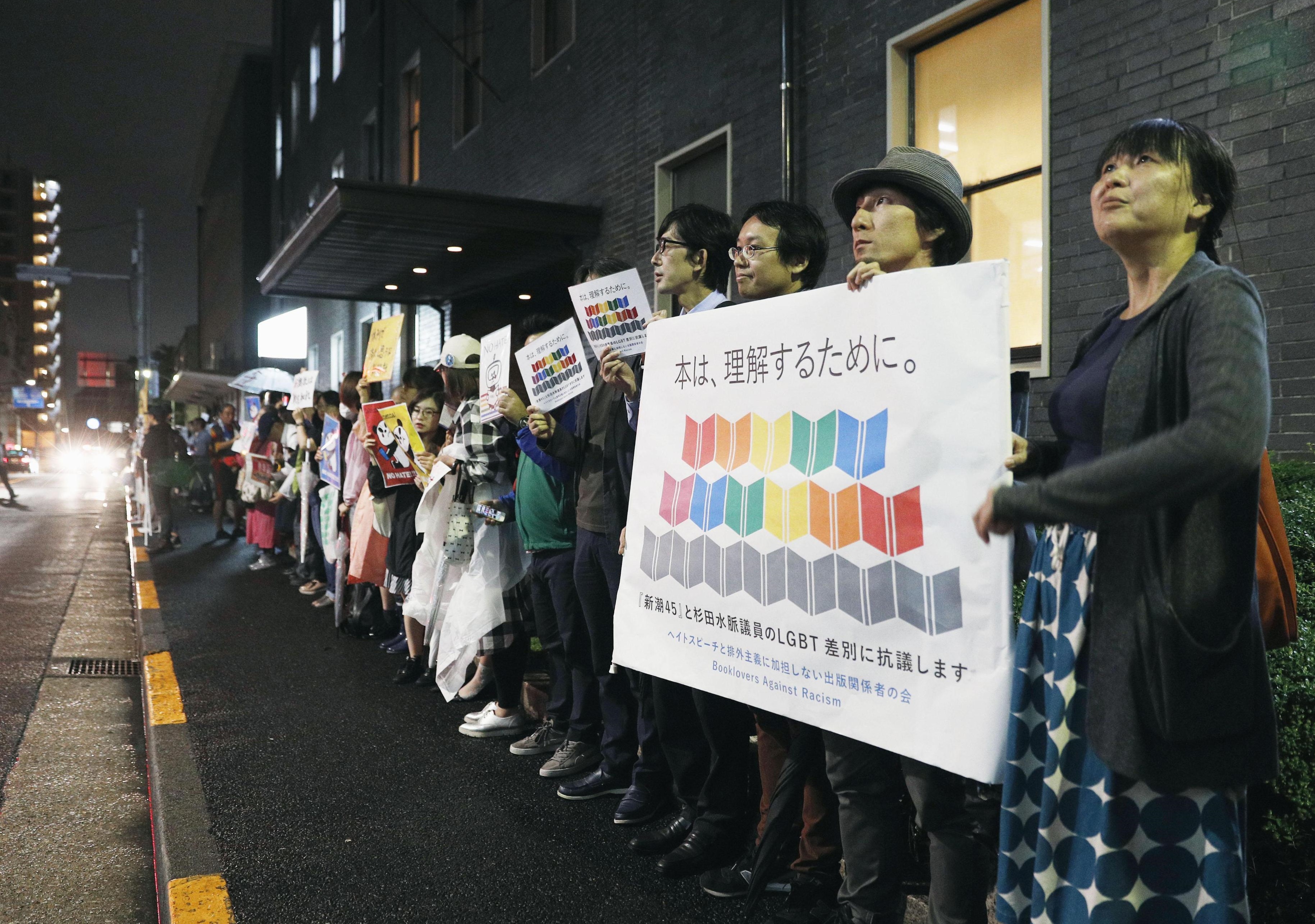 People protest in front of the headquarters of Shinchosha Publishing Co. in Tokyo’s Shinjuku Ward on Tuesday night.  | KYODO