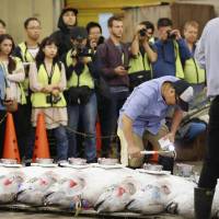 Media crews watch a tuna auction at Tsukiji market on Friday. Saturday will be the last day for the public to visit the market at its current site before the facility is relocated next month. | POOL / VIA KYODO