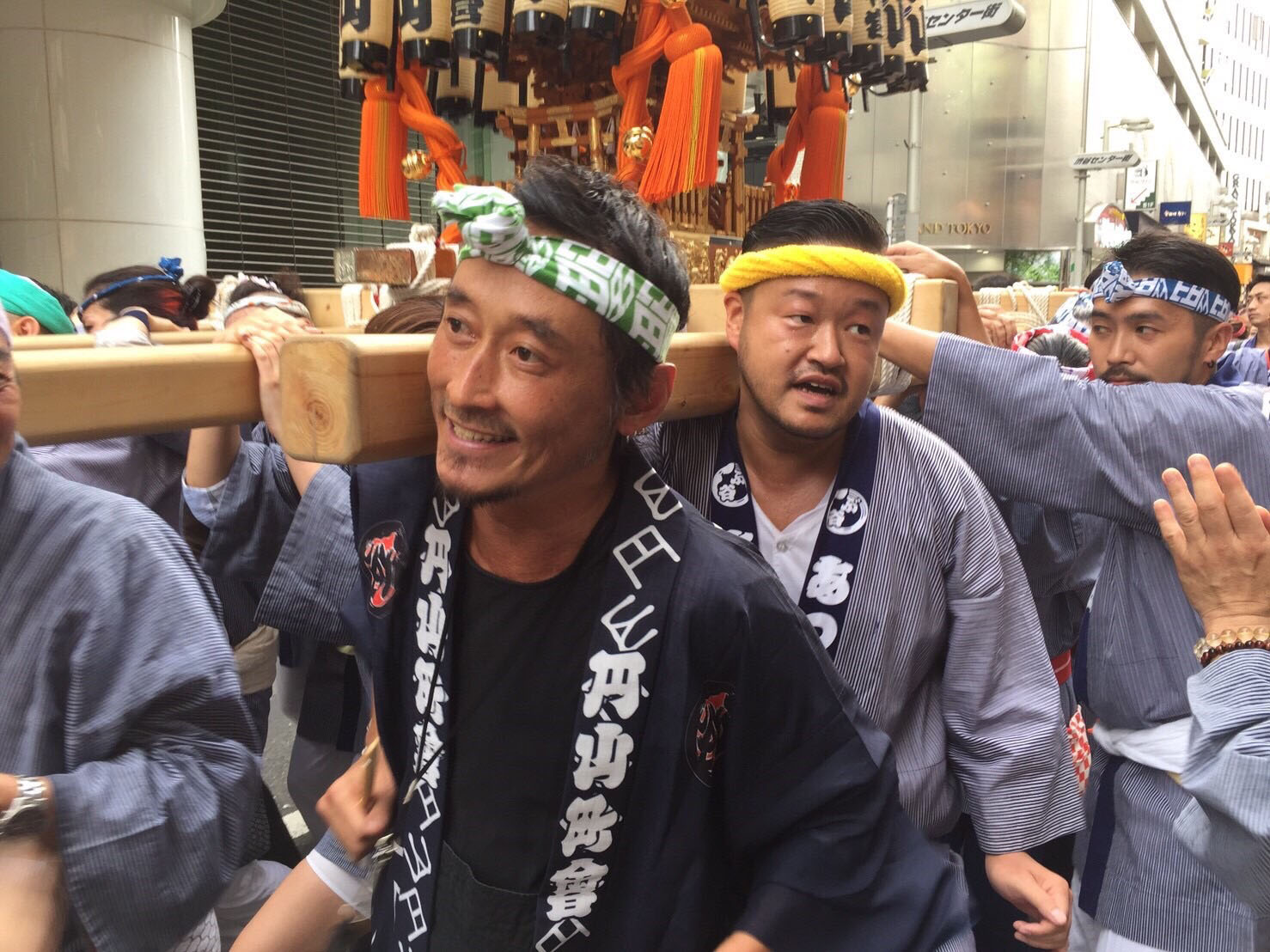 Wokini bar owner Kosuke Kurotaki (center-left) helps carry a mikoshi (festival float) for a Shibuya summer festival. | COURTESY OF MARUYAMACHO NEIGHBORHOOD ASSOCIATION