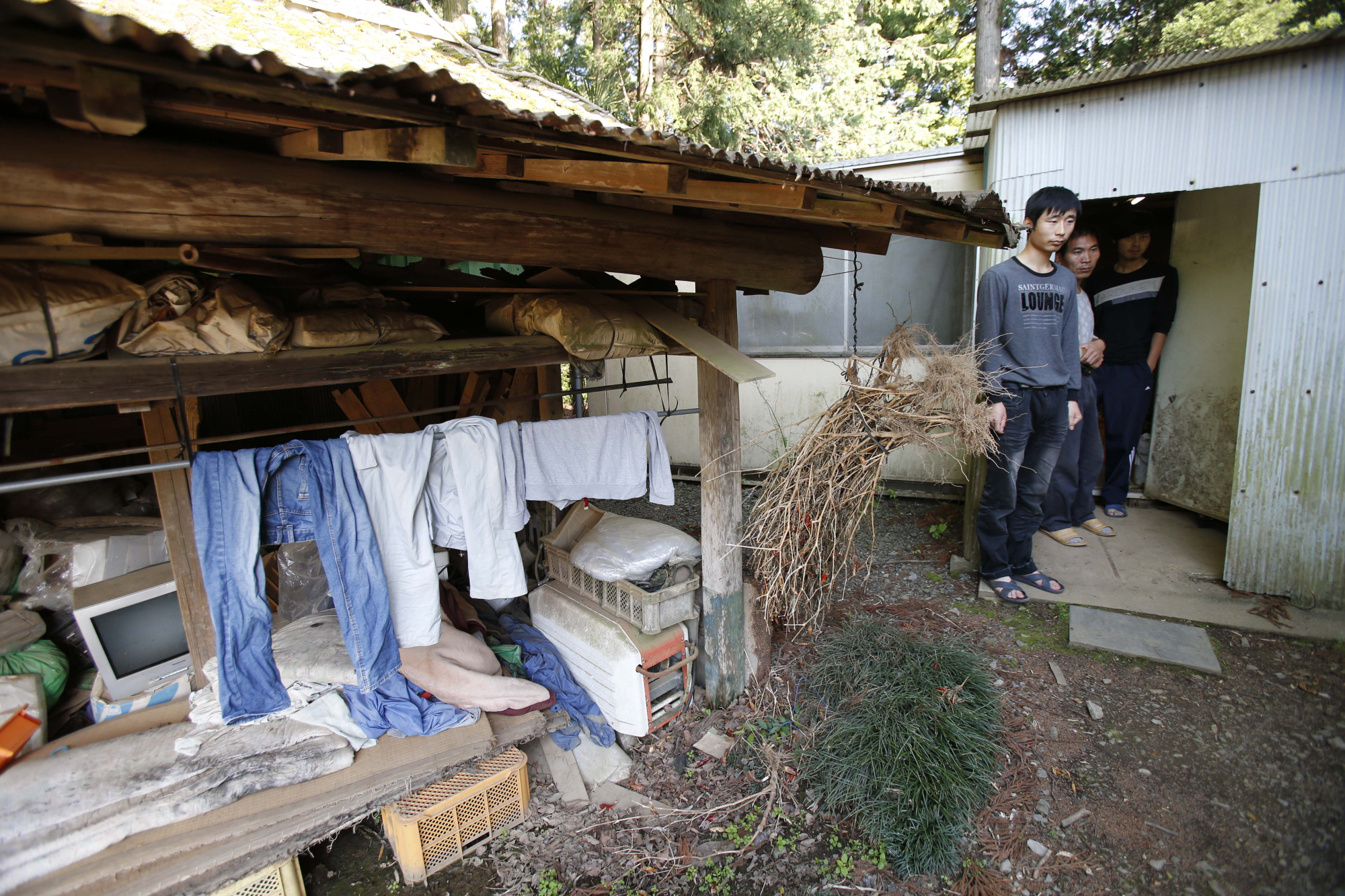 Chinese men participating in the Technical Intern Training Program stand in front of their dormitory in Hokota, Ibaraki Prefecture, in May 2013. The government has expanded this program to fill a severe shortage of unskilled labor. | AP